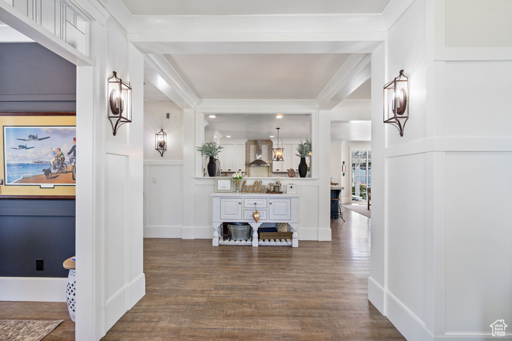 Hallway featuring a decorative wall, dark wood-style flooring, and crown molding