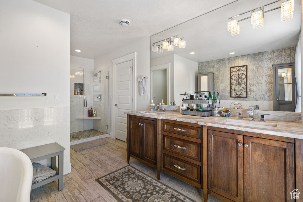 Bathroom featuring a shower stall, double vanity, wood finished floors, recessed lighting, and a freestanding bath