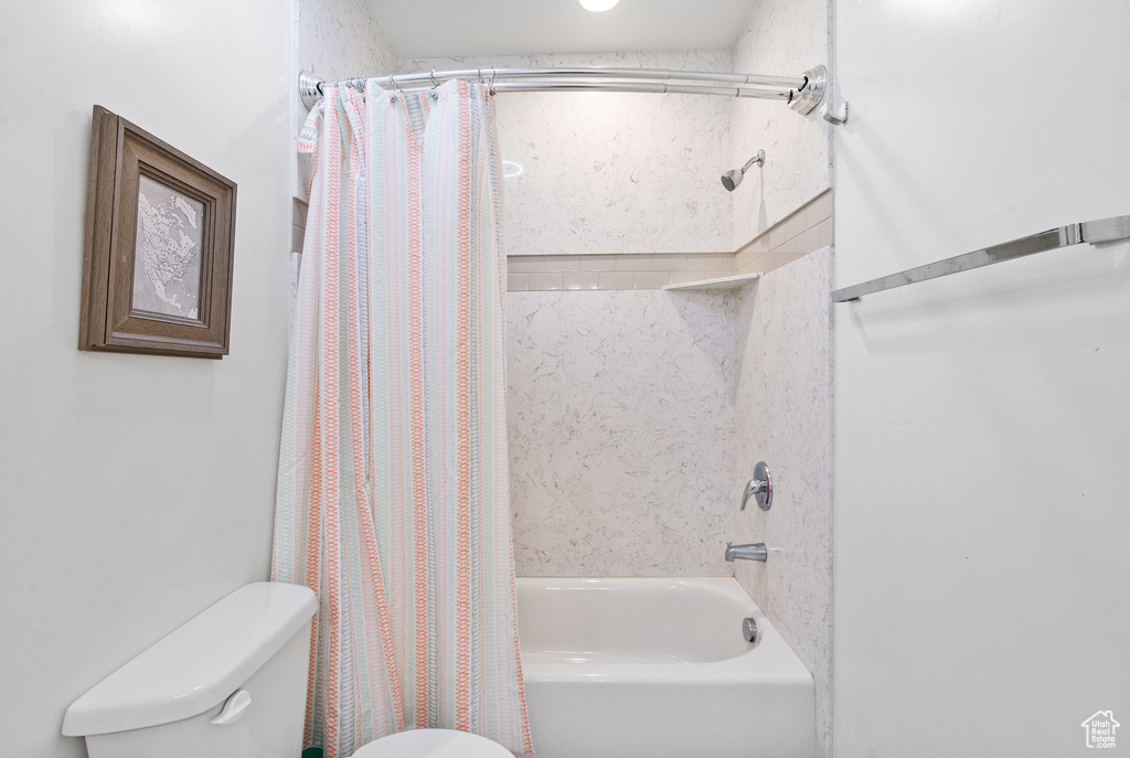 Bathroom featuring toilet and shower / bathtub combination with curtain