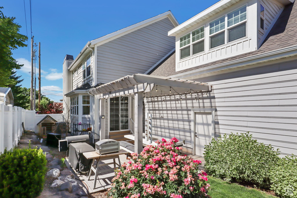 Rear view of house with a patio area, a pergola, a fenced backyard, a chimney, and a shingled roof