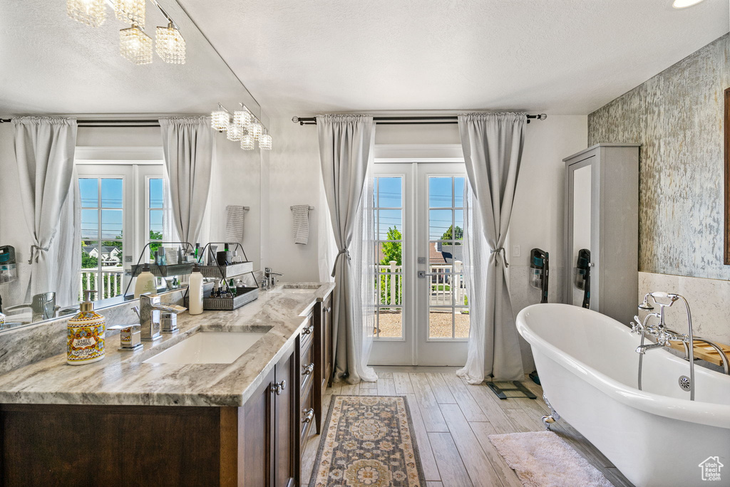 Full bath with a chandelier, healthy amount of natural light, double vanity, and a freestanding bath