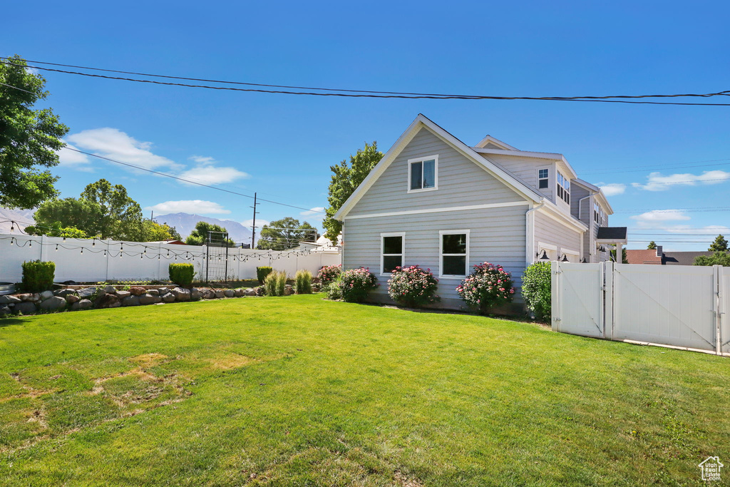Back of property with an attached garage, a gate, and a fenced backyard