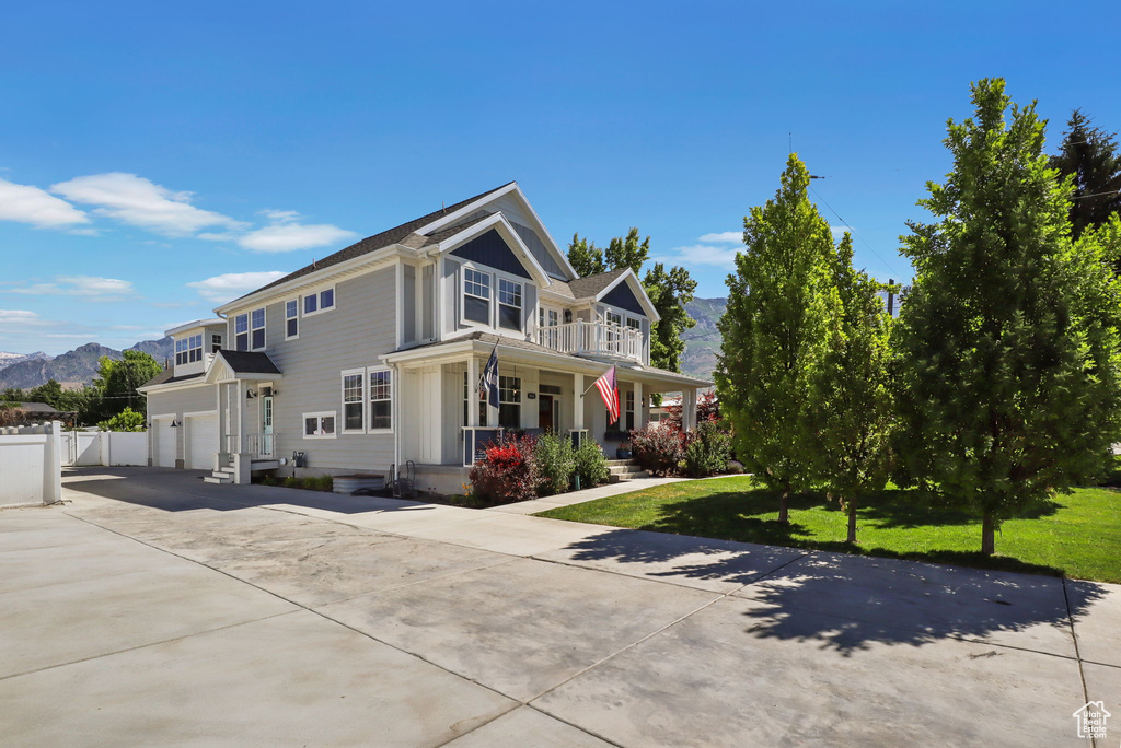 View of home's exterior featuring covered porch, concrete driveway, an attached garage, a mountain view, and a balcony