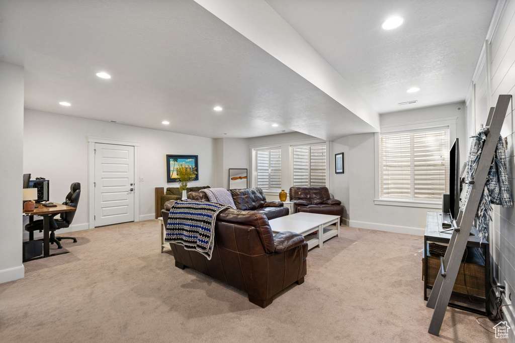 Living area with light carpet, recessed lighting, and a desk