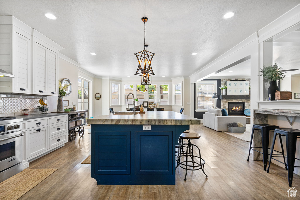 Kitchen with high end stainless steel range, a breakfast bar, white cabinetry, plenty of natural light, and recessed lighting