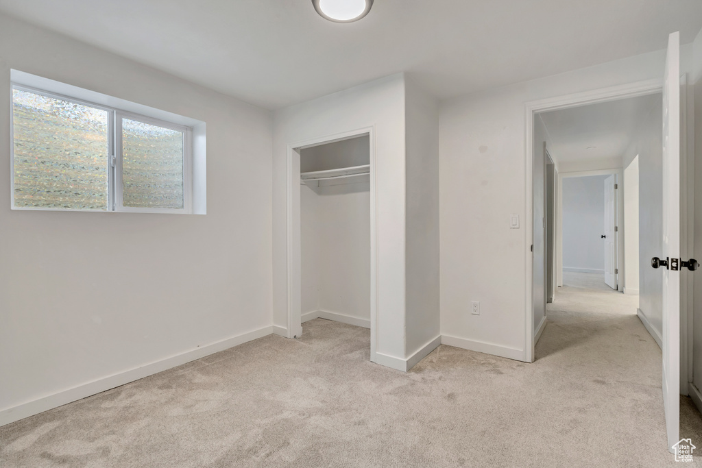 Unfurnished bedroom with light colored carpet and a closet