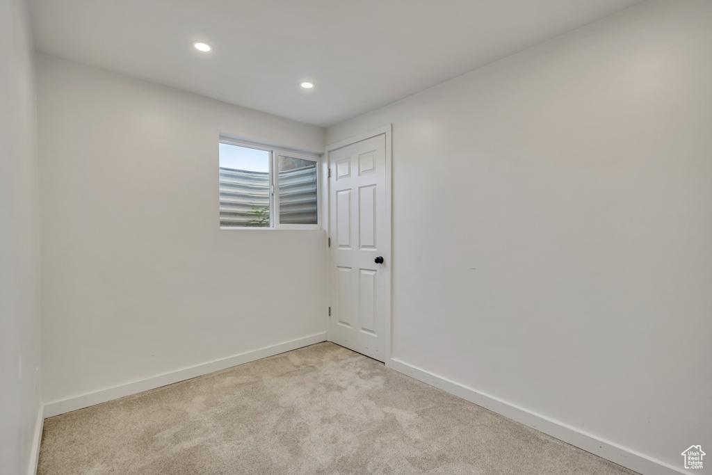 Empty room with light colored carpet and recessed lighting