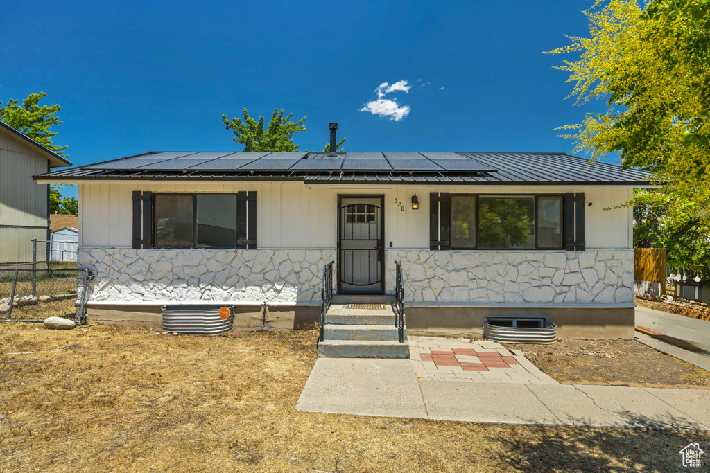 View of front facade featuring roof mounted solar panels, a metal roof, and a porch