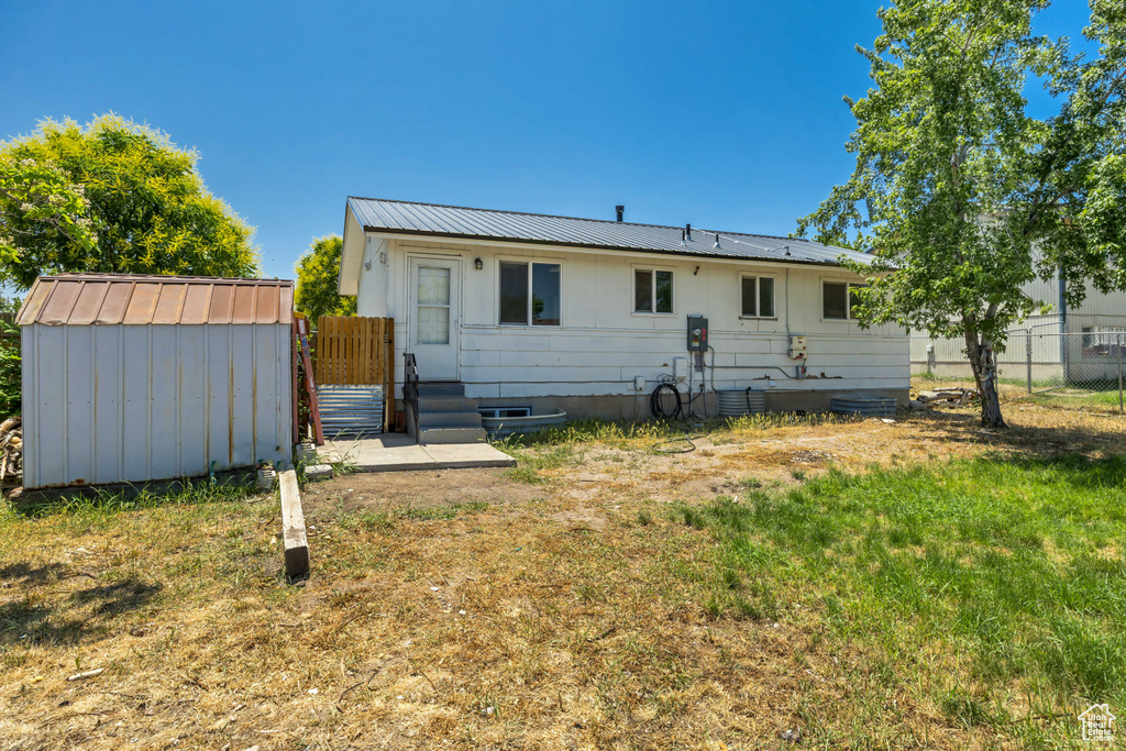 Rear view of property with a storage shed and a metal roof