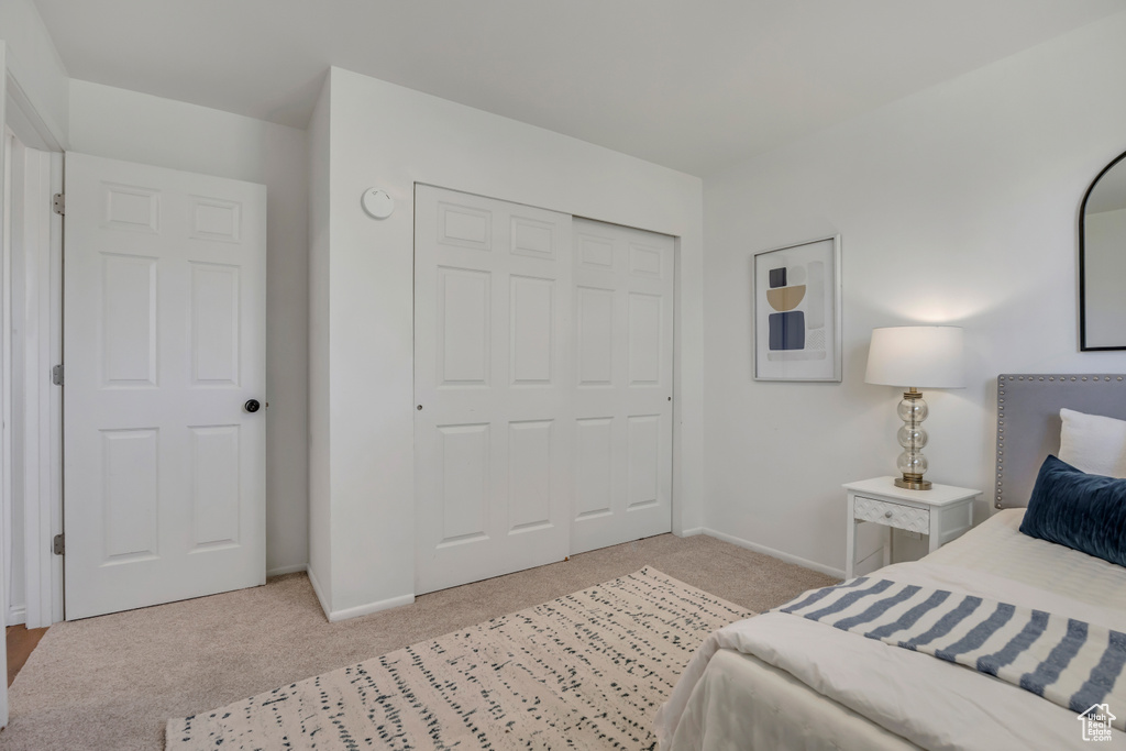Bedroom with light colored carpet and a closet