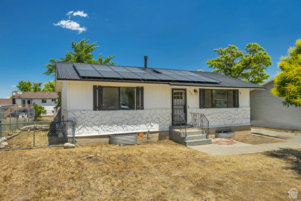 View of front of property featuring roof mounted solar panels and a metal roof