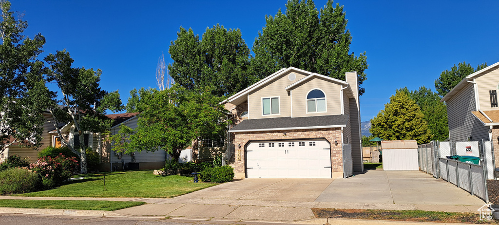 Traditional-style home with concrete driveway, a garage, a chimney, and brick siding