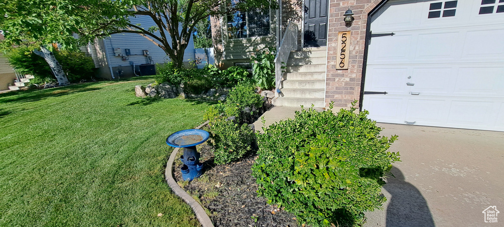 View of green lawn with an attached garage