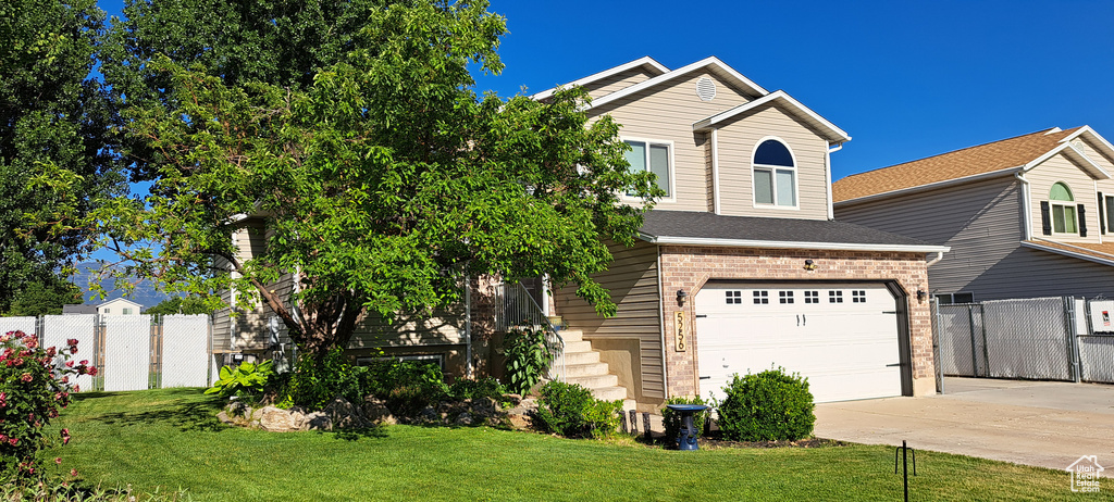 View of front facade with driveway, brick siding, and an attached garage