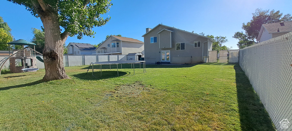 Fenced backyard with a trampoline and a playground