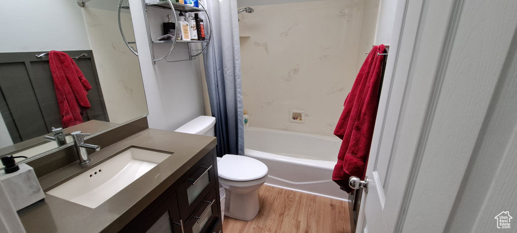 Full bathroom featuring wood finished floors, vanity, and shower / tub combo with curtain