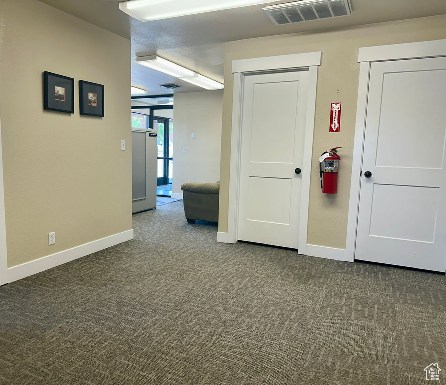 Corridor featuring dark carpet and baseboards
