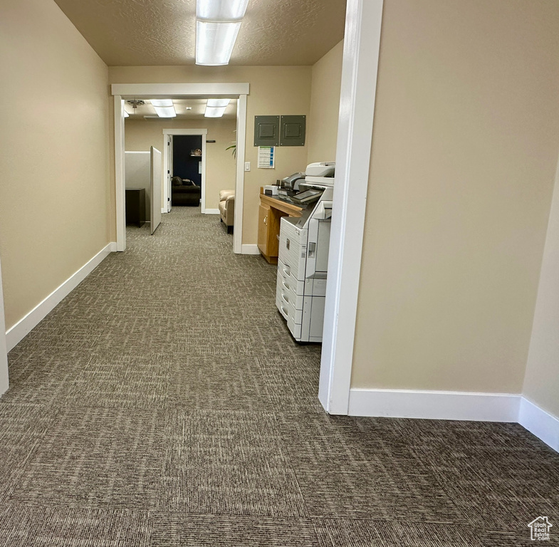 Hallway featuring dark carpet and a textured ceiling