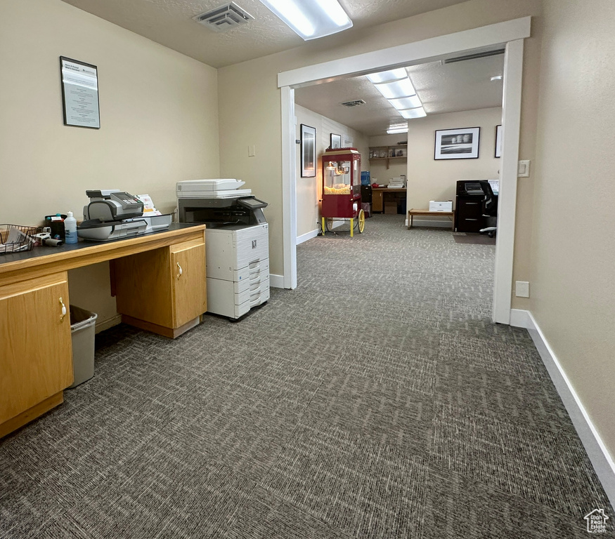 Home office with dark colored carpet and baseboards