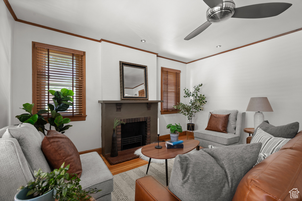 Living area featuring wood finished floors, a ceiling fan, ornamental molding, a fireplace, and recessed lighting