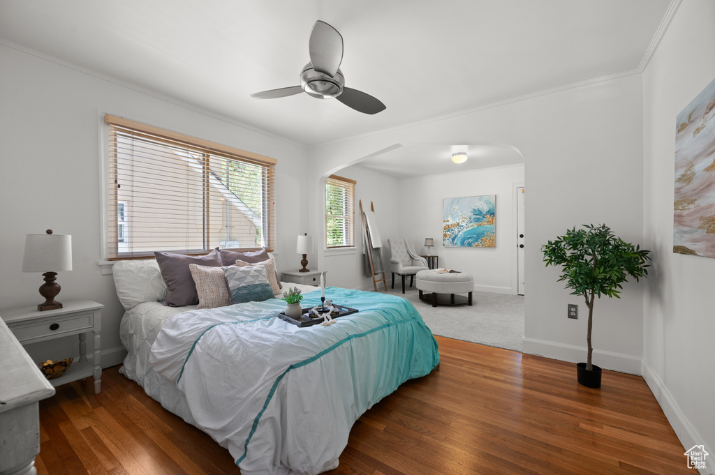 Bedroom featuring arched walkways, wood finished floors, ceiling fan, and ornamental molding