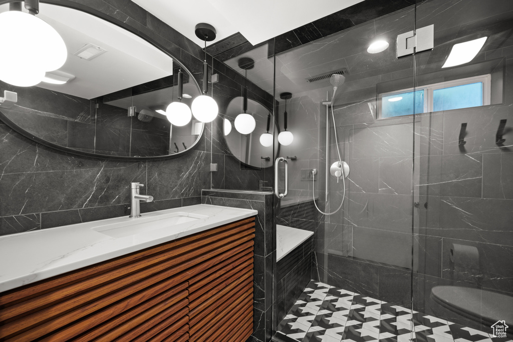 Bathroom featuring tile walls, vanity, and a shower stall