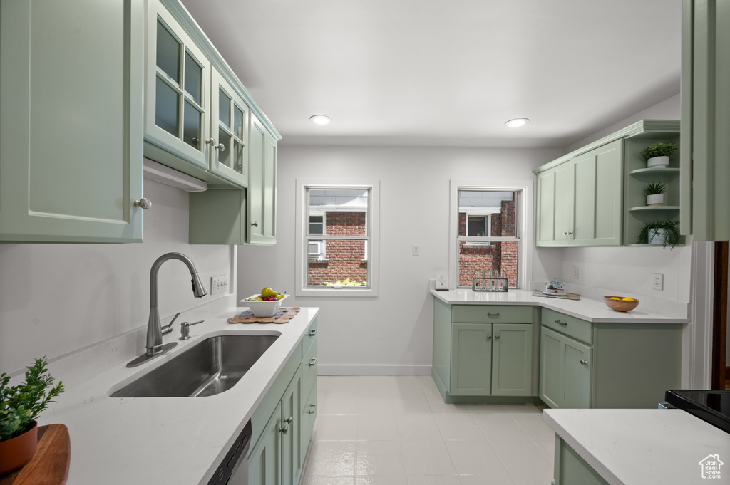 Kitchen with green cabinets, light countertops, open shelves, glass insert cabinets, and recessed lighting