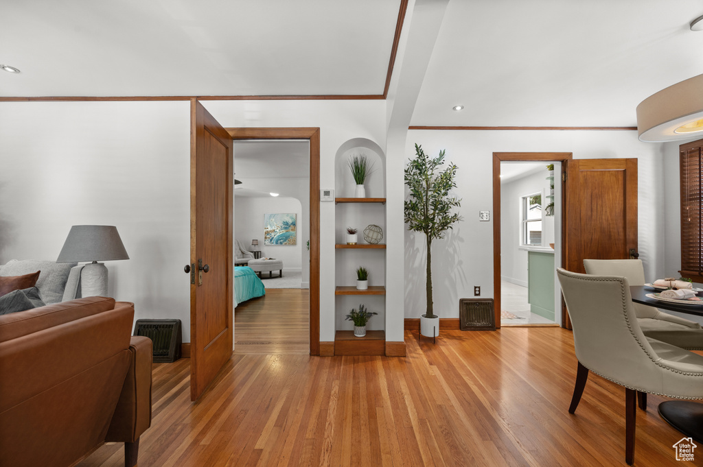 Office area featuring light wood-style floors, built in features, and ornamental molding