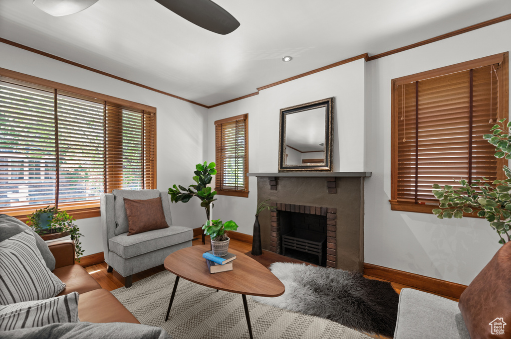 Living area with wood finished floors, ornamental molding, a brick fireplace, ceiling fan, and recessed lighting