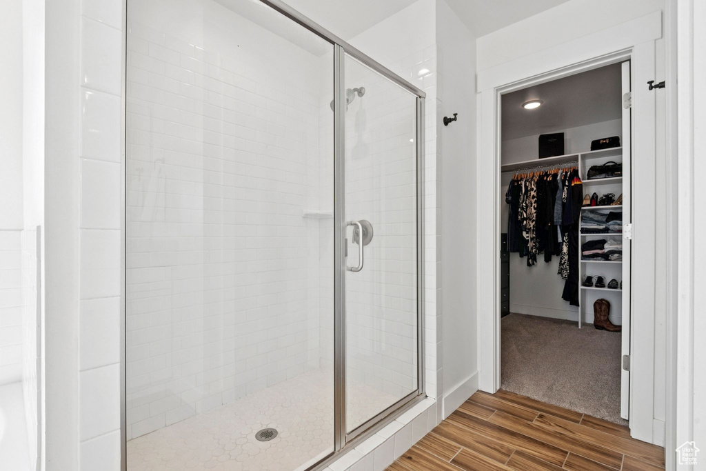 Bathroom with a shower stall, a walk in closet, and wood finished floors