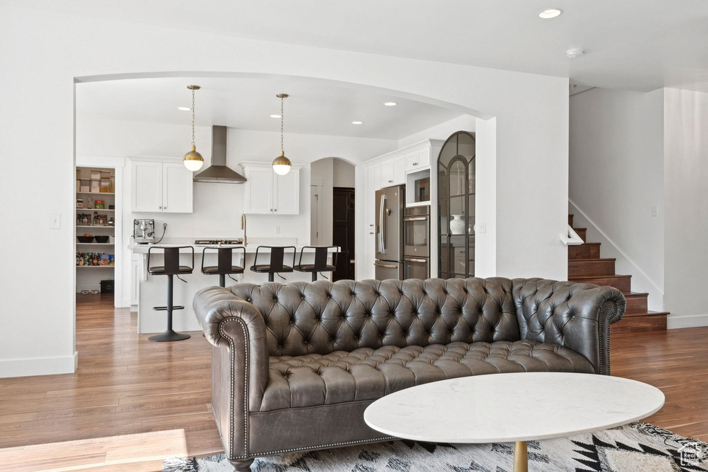 Living area with arched walkways, light wood finished floors, recessed lighting, and stairway