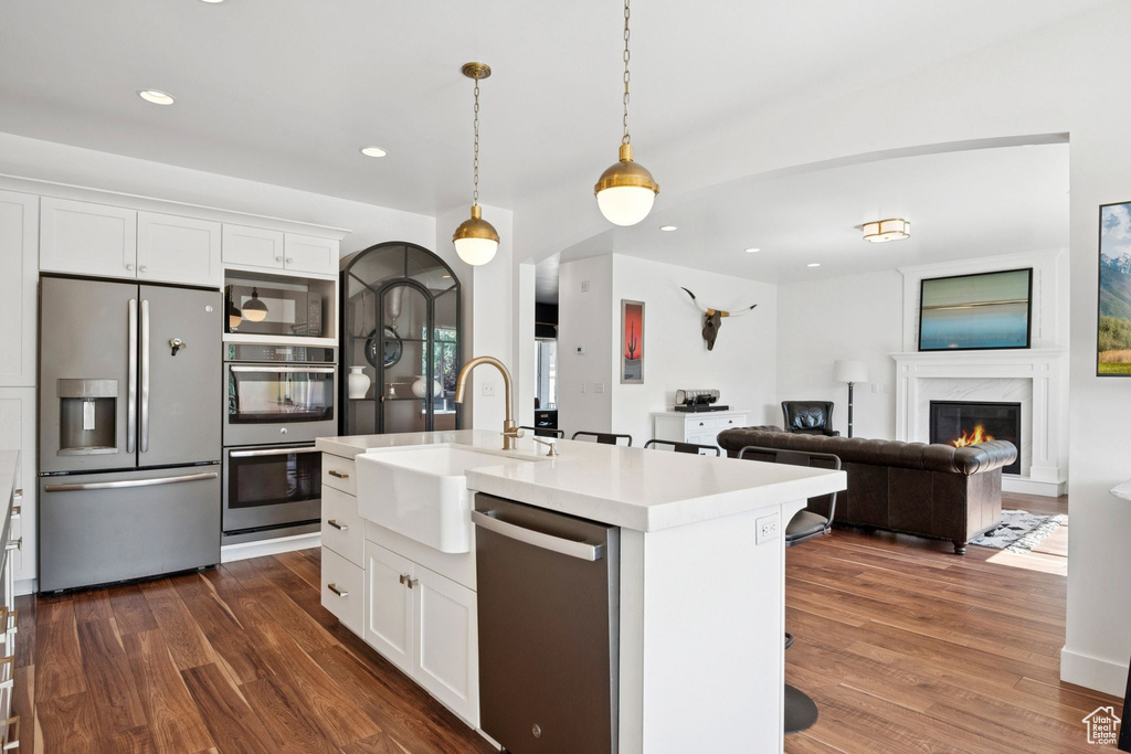 Kitchen featuring stainless steel appliances, dark wood-style flooring, light countertops, recessed lighting, and white cabinets