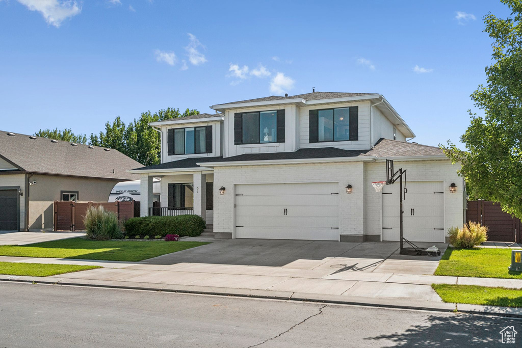 View of front facade with driveway, an attached garage, and a gate
