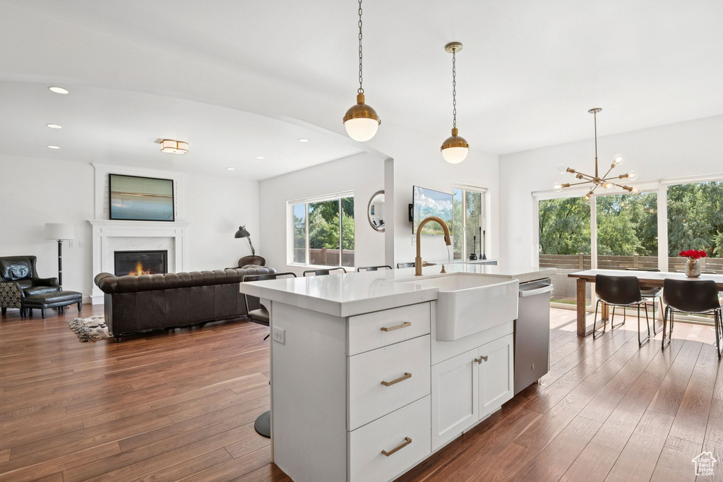 Kitchen featuring dishwasher, light countertops, open floor plan, pendant lighting, and dark wood finished floors