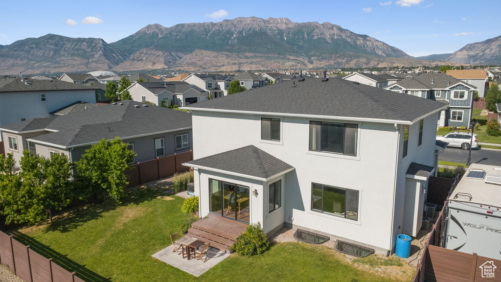 Back of property with a residential view, a mountain view, stucco siding, roof with shingles, and a patio area