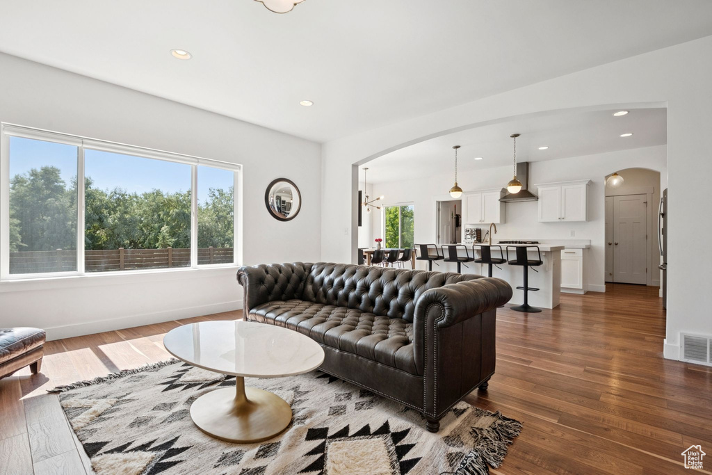 Living area with arched walkways, wood finished floors, and recessed lighting