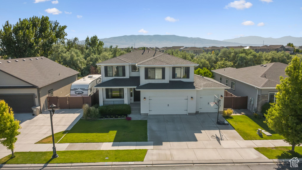 Traditional home featuring driveway, a gate, a shingled roof, and a mountain view