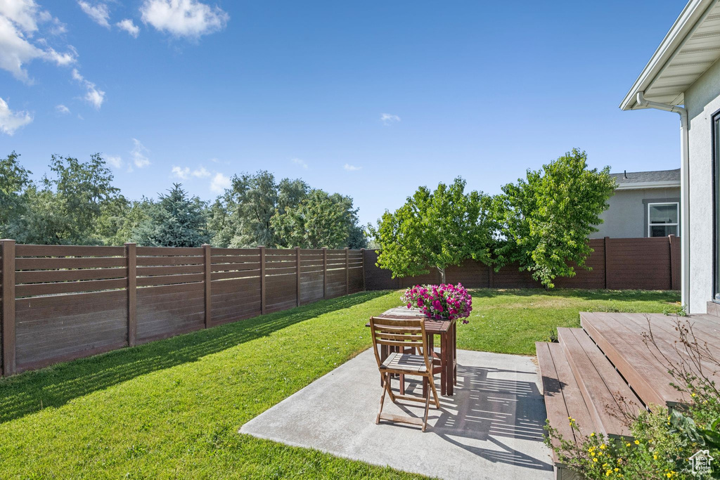 Fenced backyard featuring a patio and a wooden deck