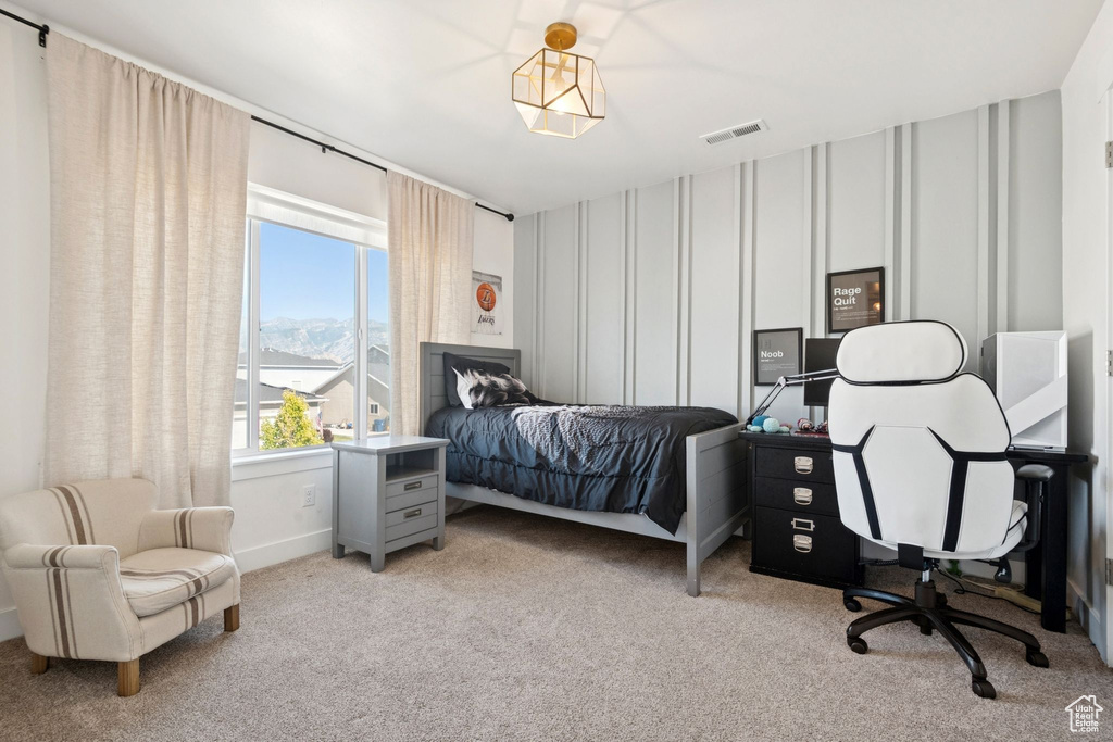 Bedroom featuring carpet flooring, a decorative wall, and an office area