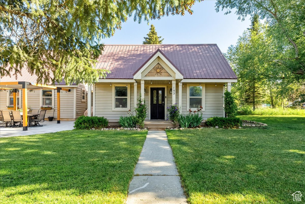 View of front of house with a front yard, a metal roof, and a patio