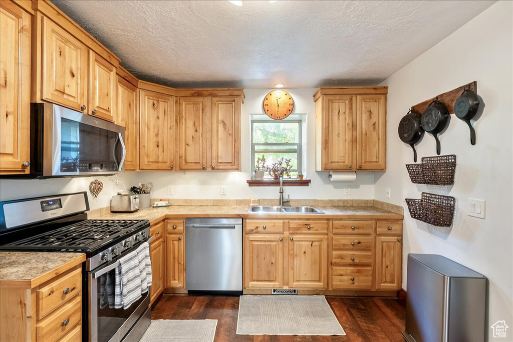 Kitchen with appliances with stainless steel finishes, dark wood-style floors, and a textured ceiling