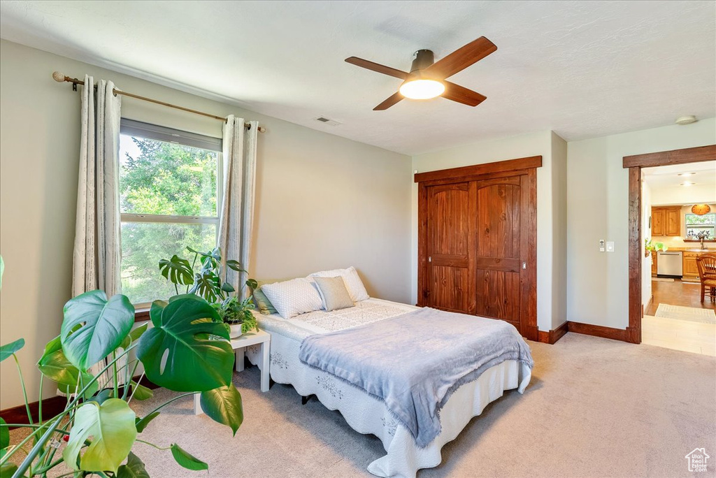 Bedroom featuring light colored carpet, a closet, and ceiling fan