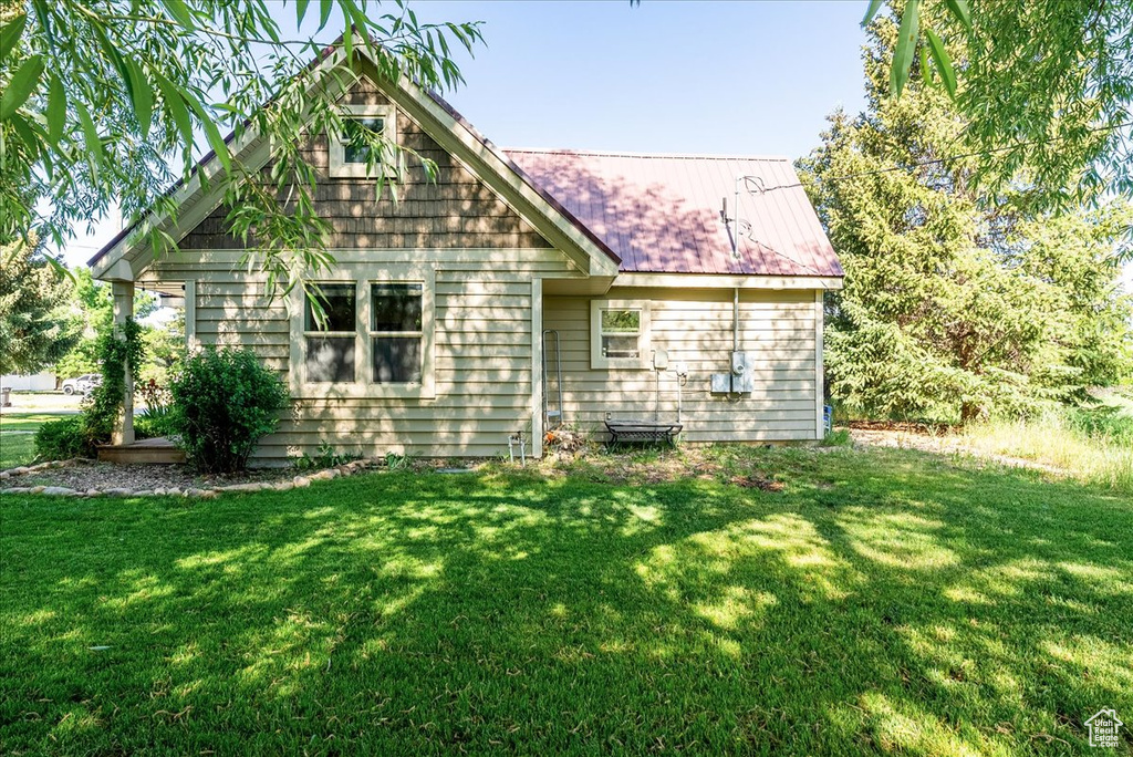 Back of house with a yard and a metal roof