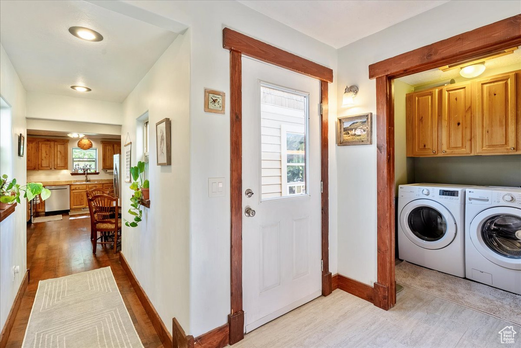 Washroom featuring washer and clothes dryer, cabinet space, dark wood-style flooring, and healthy amount of natural light