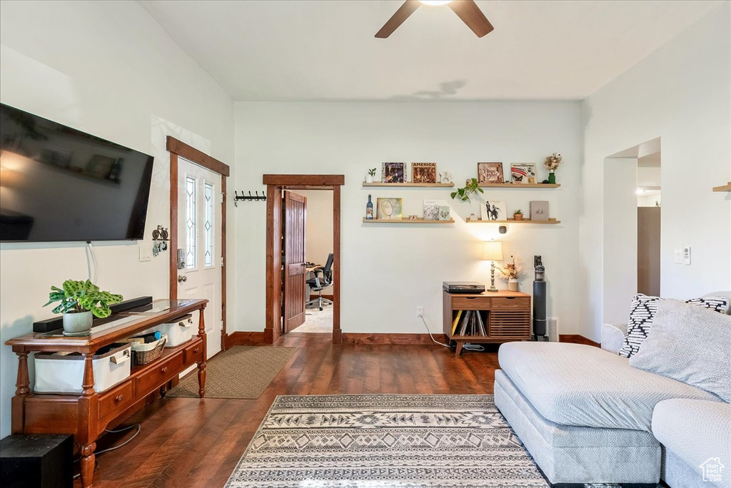 Living area featuring a ceiling fan and dark wood-type flooring