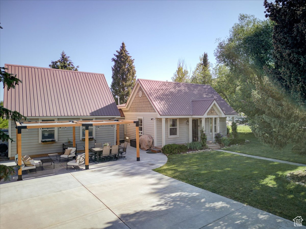 View of front of property with a metal roof, a front lawn, outdoor dining area, and a patio area