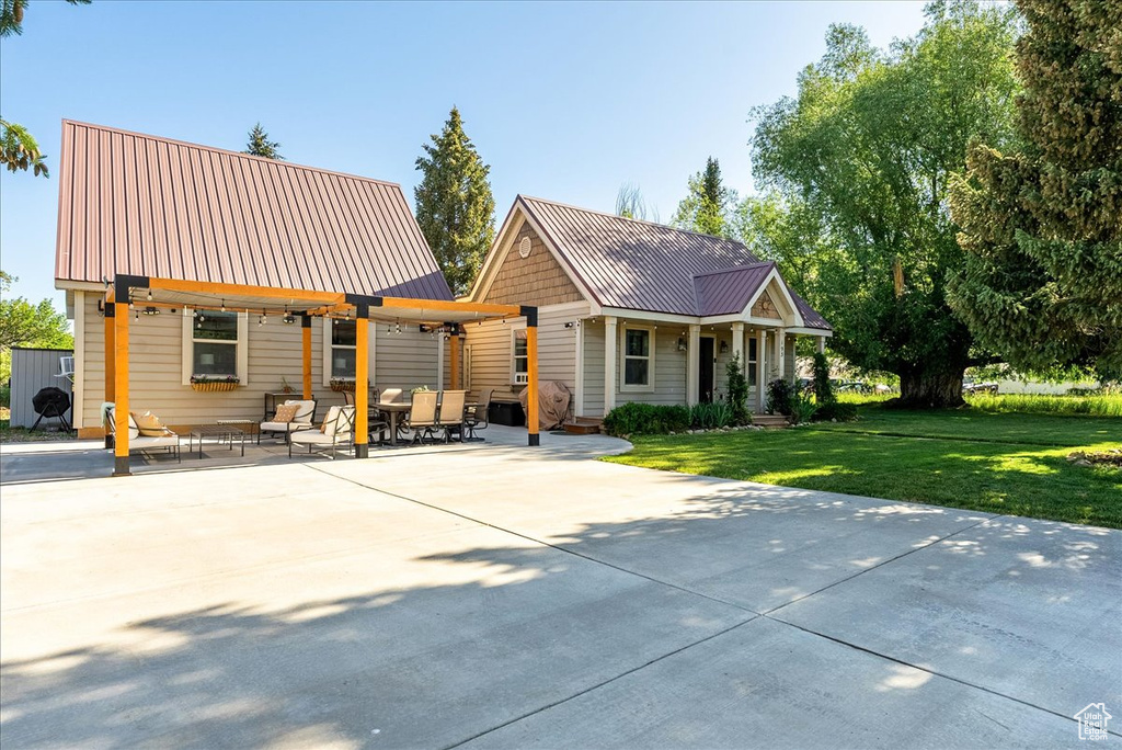 View of front of property featuring a metal roof, a front yard, and a patio area