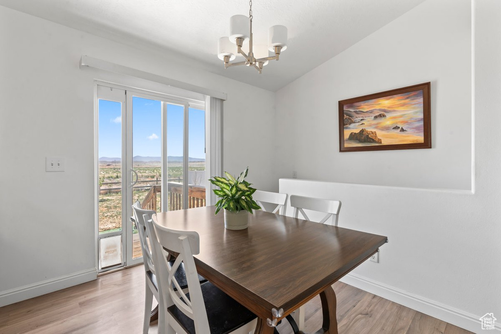 Dining area featuring a chandelier, light wood-style floors, a mountain view, and vaulted ceiling