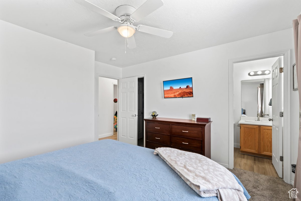 Bedroom featuring ensuite bathroom, wood finished floors, and a ceiling fan