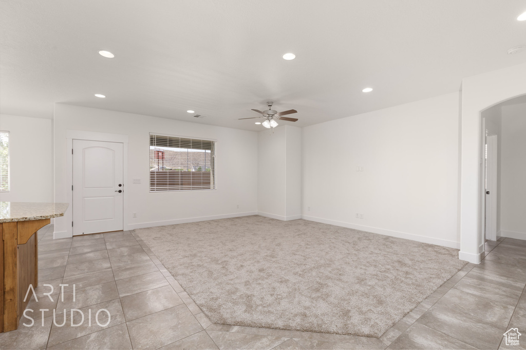 Unfurnished living room featuring light tile patterned floors, recessed lighting, arched walkways, and ceiling fan